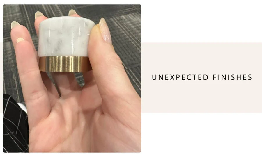 Polished marble and brass ring with unexpected finish detail, held by a person with manicured nails, showcasing a modern jewelry design.