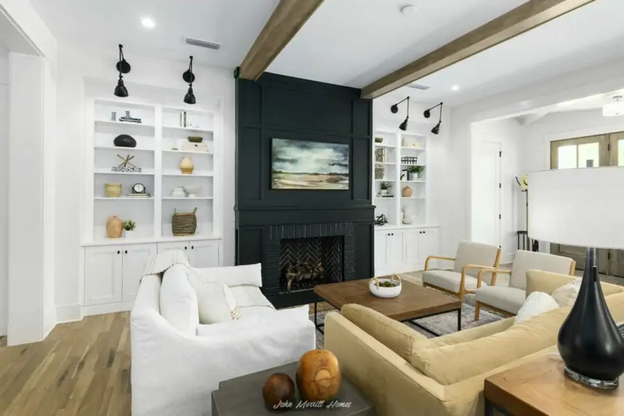 Modern living room with built-in white bookshelves, a black fireplace with a landscape painting, white and beige seating, wooden accents, and contemporary decor, bright and inviting interior design.