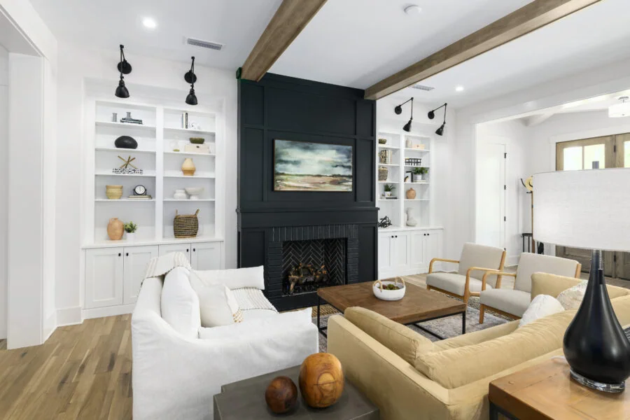 Modern living room with white walls, built-in white bookshelves, a black fireplace, and contemporary furniture including a white sofa and beige armchairs, creating a stylish and inviting space.