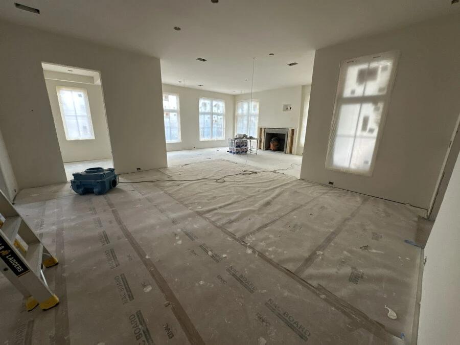Bright, open-concept interior of a new home under construction, featuring large windows, unfinished walls, and a fireplace; ready for final interior touches and decorating.