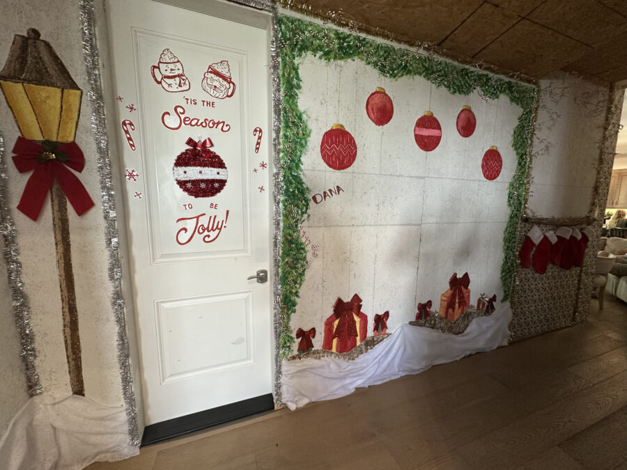 Festive holiday door decoration featuring seasonal ornaments, red bows, stockings, and personalized touches for Christmas cheer.