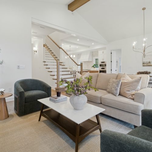 Bright, welcoming living room with neutral-toned furniture, modern decor, and large windows providing natural light in a stylish John Merrill home.