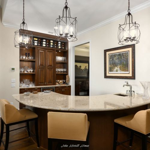 Luxurious kitchen with granite island, wooden cabinetry, and stylish lighting fixtures, ideal for entertaining and family gatherings.