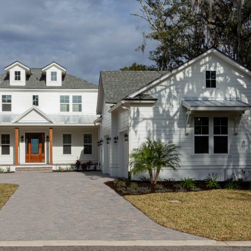 Beautiful white two-story home with a welcoming front porch, surrounded by a well-maintained lawn and landscaping, showcasing contemporary architectural design.