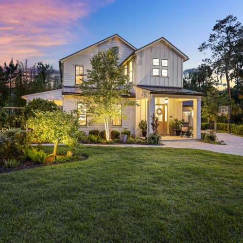 Beautiful two-story house with a well-maintained front yard, lush greenery, and a clear evening sky, showcasing a welcoming residential property.