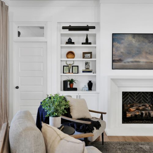 Bright and inviting living room featuring a cozy fireplace, built-in shelves with decorative items, and comfortable seating arrangements. Perfect for relaxing and entertaining guests.
