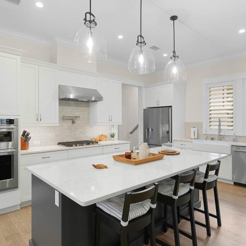Bright, spacious kitchen featuring white cabinetry, a large island with seating, and stainless steel appliances, perfect for family cooking and entertaining.