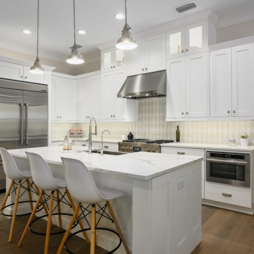Bright, modern kitchen featuring white cabinets, stainless steel refrigerator, and island with seating, perfect for family cooking and entertaining.
