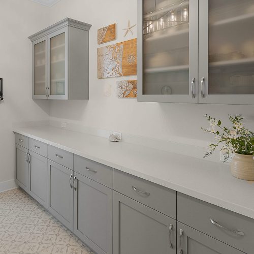 Modern kitchen with light gray cabinets and white countertops.