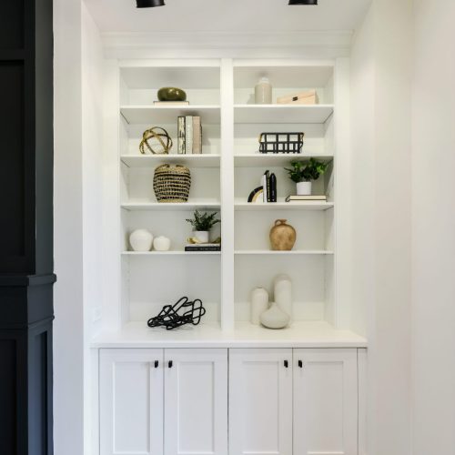 Built-in white bookshelf with decorative objects and books in a well-lit room.