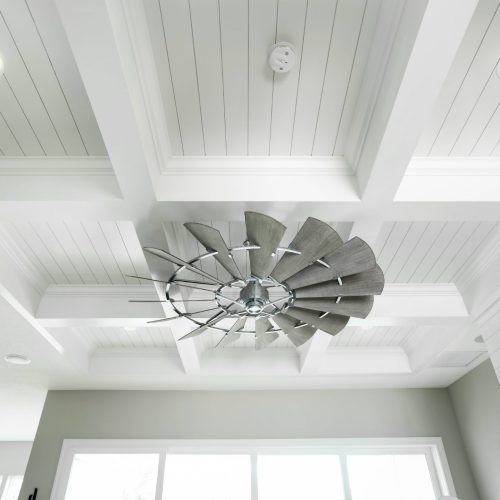 Elegant ceiling fan featuring a contemporary spiral blade design, installed on a white coffered ceiling in a bright, airy living space.