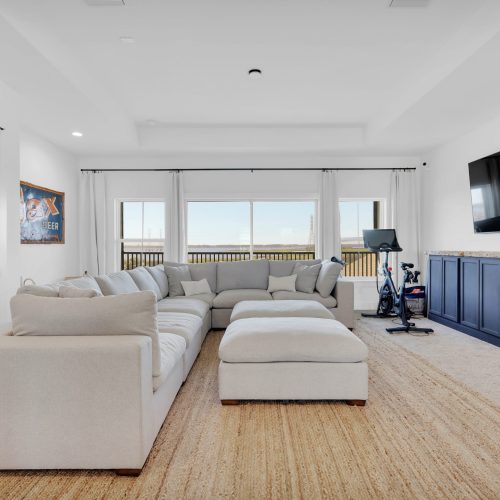 Bright and spacious living room with large windows, white walls, and a comfortable sectional sofa, perfect for relaxing and enjoying scenic views.