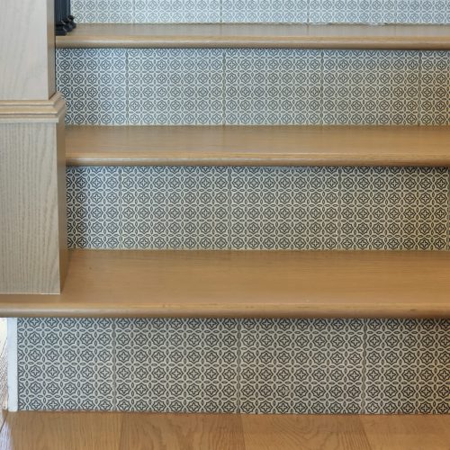 A close-up of a staircase featuring wooden treads and patterned tile risers, highlighting stylish interior design elements.