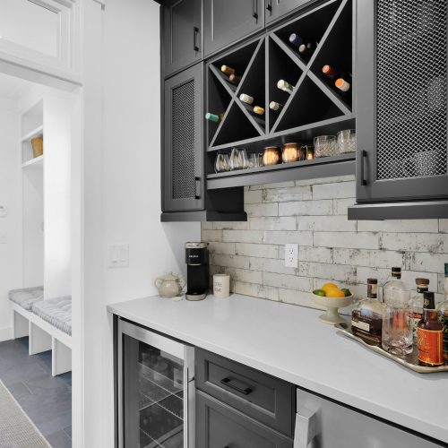 Stylish kitchen featuring built-in wine racks, a white countertop, and a brick backsplash, perfect for entertaining and everyday use.