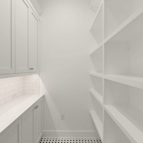 Bright and spacious pantry featuring white cabinetry and open shelving, ideal for organized storage in a contemporary home.