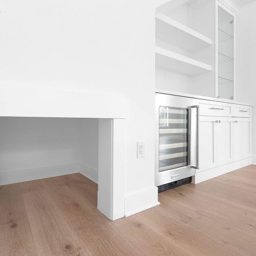 Bright, modern kitchen featuring white cabinetry, a built-in wine cooler, and open shelving, perfect for contemporary living and entertaining.