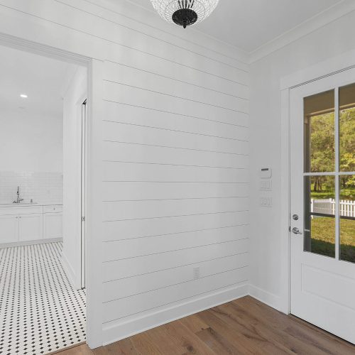 Bright and welcoming entryway with white walls, a glass-paneled door, and natural light.