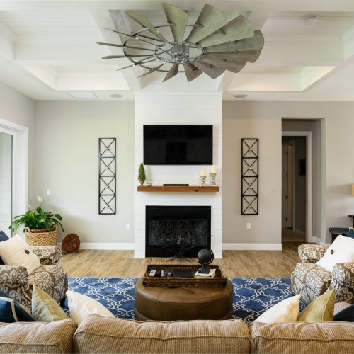 Spacious living room featuring a fireplace, wall-mounted TV, and elegant furniture with decorative pillows, plants, and artwork, creating a welcoming and contemporary atmosphere.
