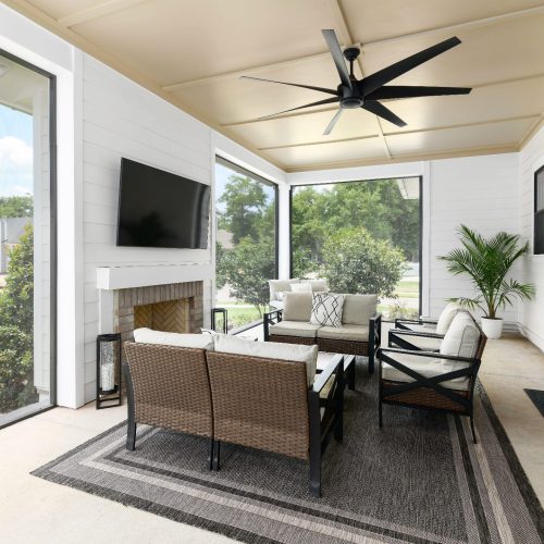 Bright and inviting screened porch featuring comfortable outdoor furniture, a ceiling fan, and large windows that offer scenic views of the surrounding greenery.