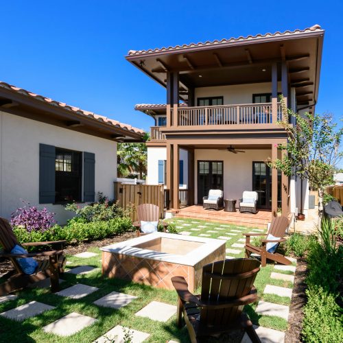 Beautiful two-story home featuring a spacious balcony and inviting backyard with seating area and fire pit. Perfect for outdoor entertaining and relaxing in a sunny climate.
