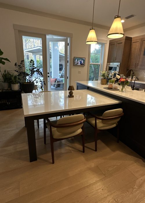 Bright, inviting kitchen featuring a large island, pendant lighting, and ample natural light from sliding doors.