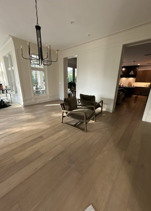 Spacious living area featuring a contemporary chandelier, large windows, and cozy seating, showcasing a stylish and inviting home interior.