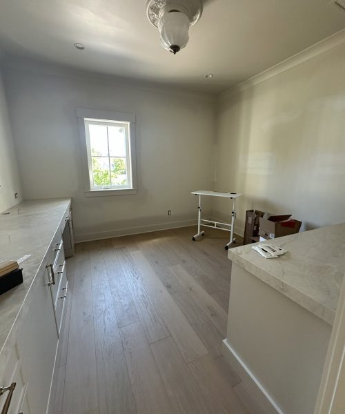 Bright kitchen with white cabinetry, a window providing natural light, and a clean, minimalist style.