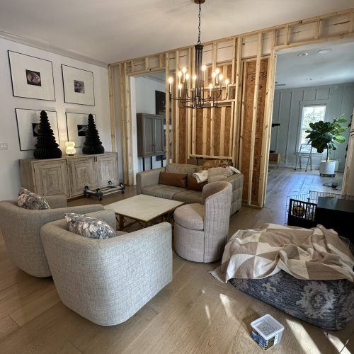 1. Modern living room with neutral-toned furniture, wooden flooring, stylish decor, and an open-plan design, part of a custom-built home by John Merrill Homes.