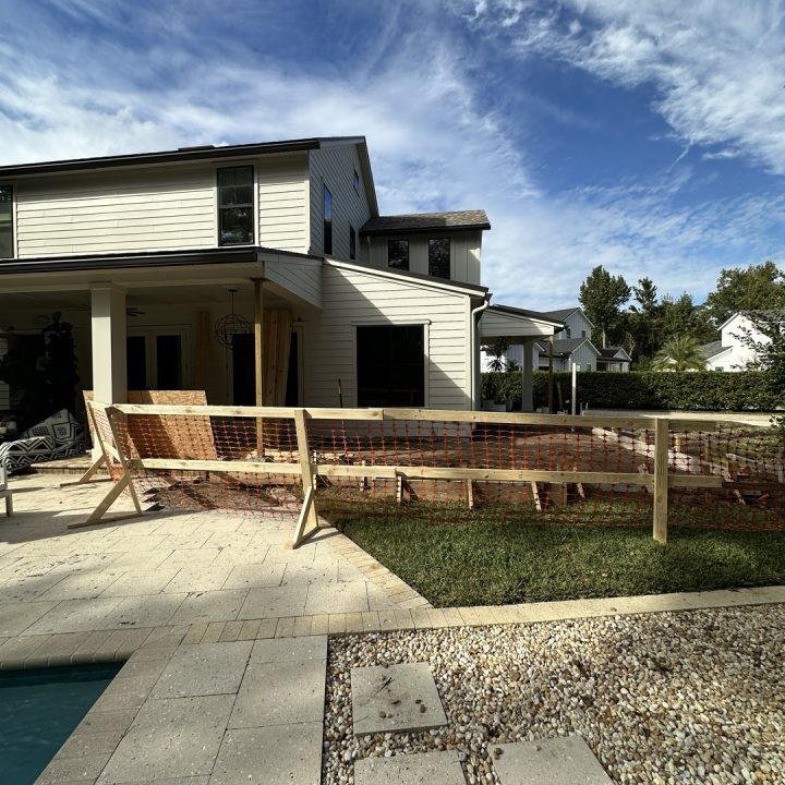 1. Modern two-story house under construction with white siding, large windows, and a backyard patio, featuring ongoing landscaping work.