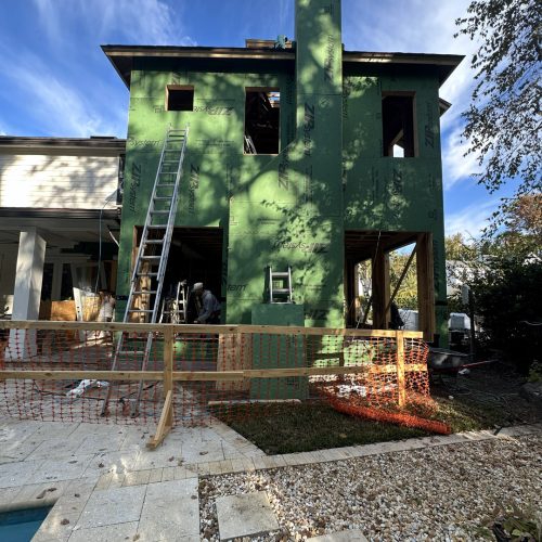 Green house under construction with scaffolding and ladders, part of a residential building project.