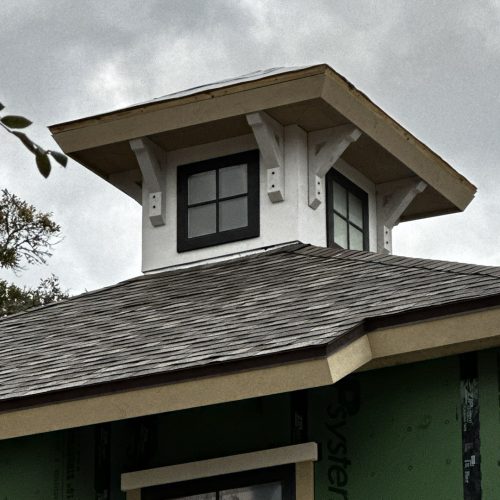 Elegant exterior of a new home under construction with a prominent dormer window, partially completed roof, and weather-resistant siding, reflecting high-quality craftsmanship and modern design.