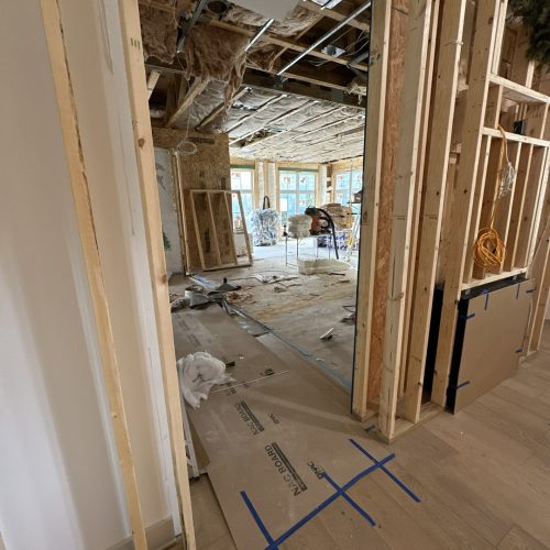 Under construction interior of a house showing exposed wooden framing, insulation, and unfinished walls during the building process.