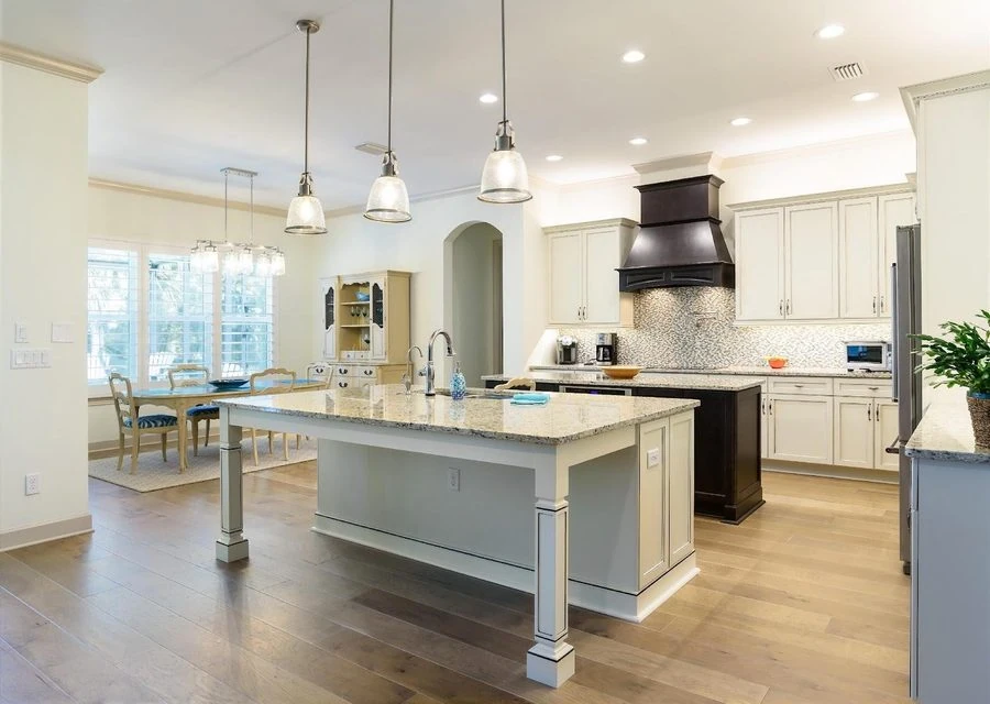 Spacious modern kitchen with white cabinets, granite countertops, and a large island for cooking and dining.