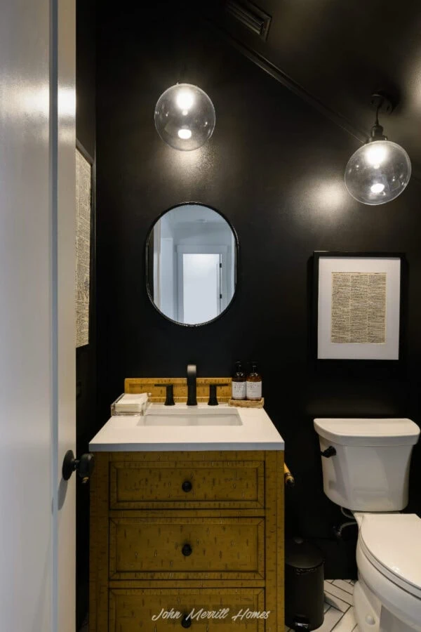Luxury black bathroom with a rustic yellow vanity, modern black fixtures, and glass globe pendant lighting, creating a sleek and stylish space.