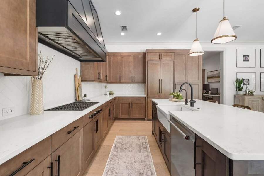 Spacious kitchen featuring warm wooden cabinets, white quartz countertops, and modern black fixtures, creating a welcoming and functional cooking space.